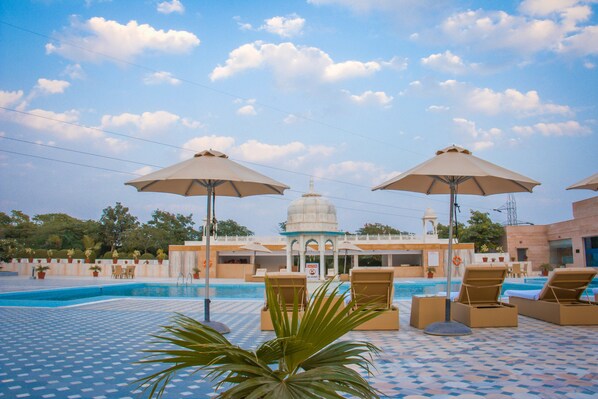 Una piscina al aire libre, sombrillas, sillones reclinables de piscina