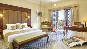 A hotel room with a large bed, a bench, a desk, and a view of the outdoors. - Pratap Mahal, Ajmer - IHCL SeleQtions (Pushkar)
