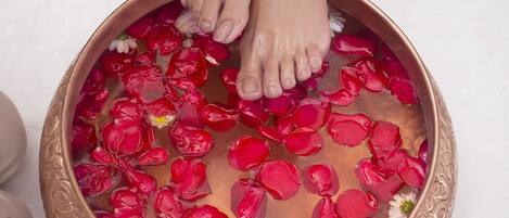 A foot soak with rose petals and a decorative bowl.