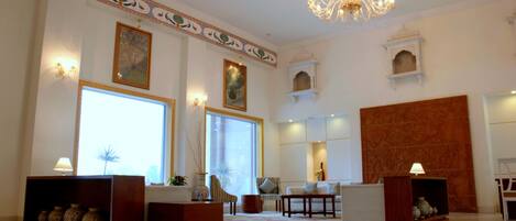 A spacious lobby with a chandelier, large windows, and traditional decor.
