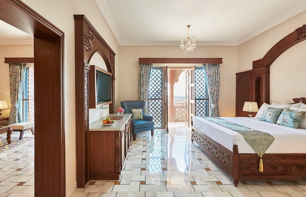 Un dormitorio amplio con una cama grande, un aparador de madera, un televisor y un balcón con vistas.