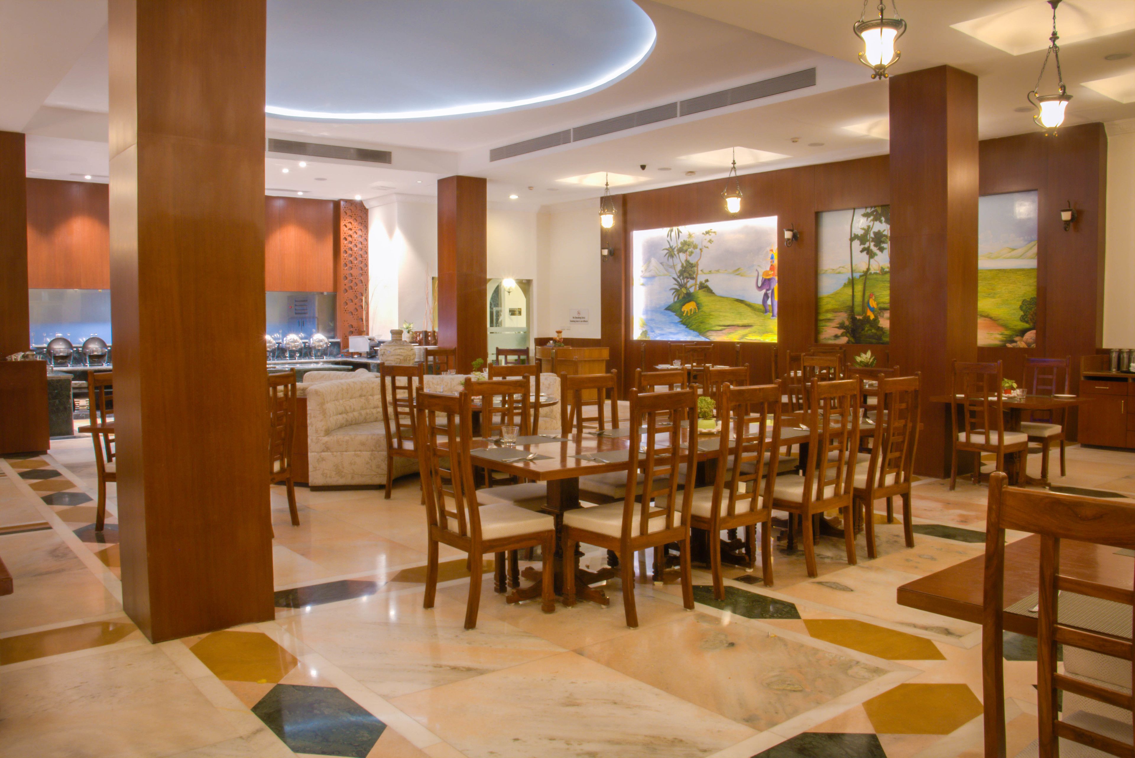 A spacious dining area with wooden tables and chairs, a marble floor, and large windows with artwork.