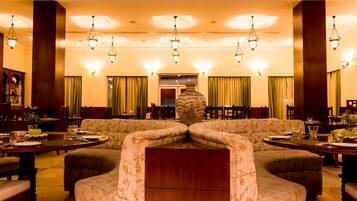 A dining area with a central round table, surrounded by sofas and chairs.
