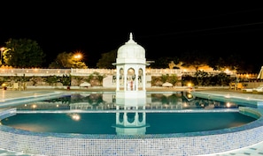 Una piscina al aire libre, sombrillas, sillones reclinables de piscina