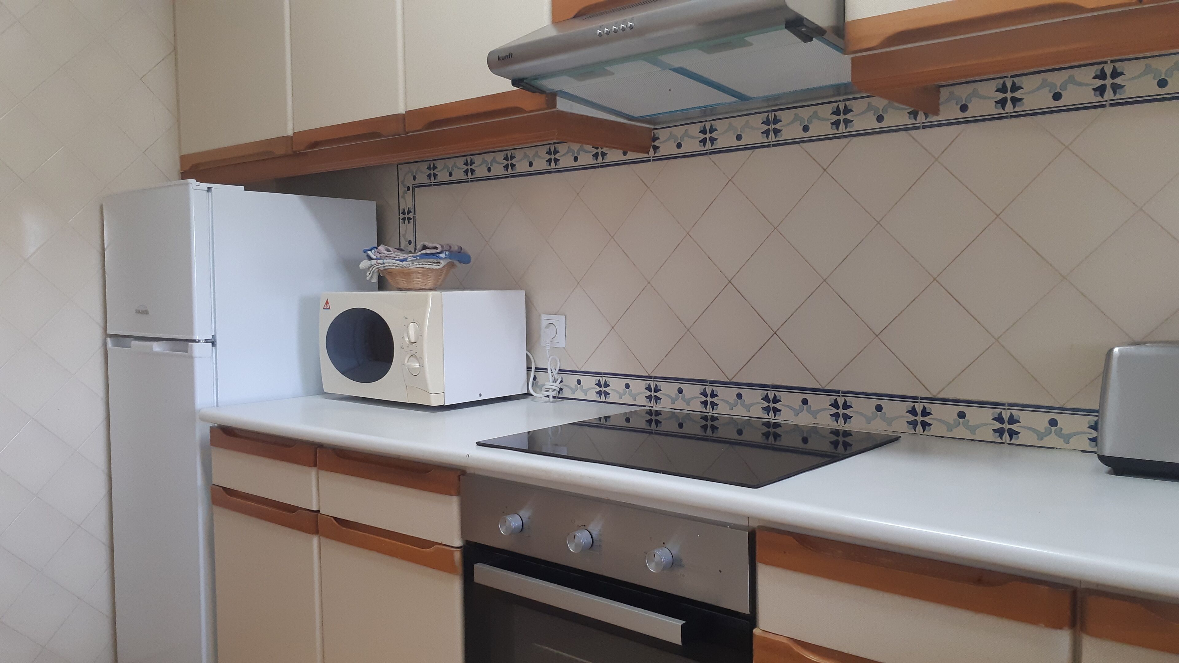 Una cocina con un refrigerador blanco, un microondas, un tostador y una estufa.
