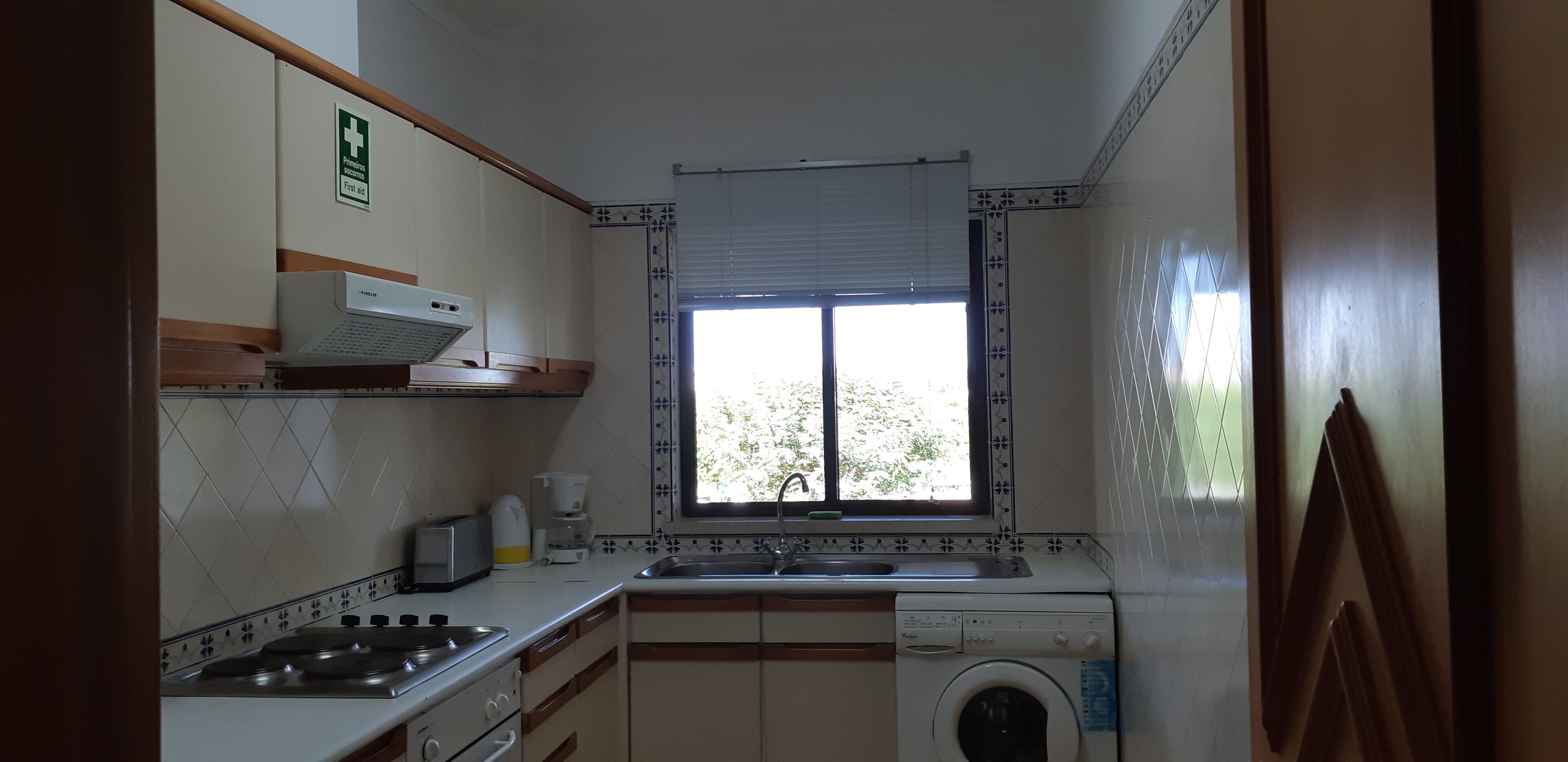 A compact kitchen with a stove, toaster, sink, and washing machine.