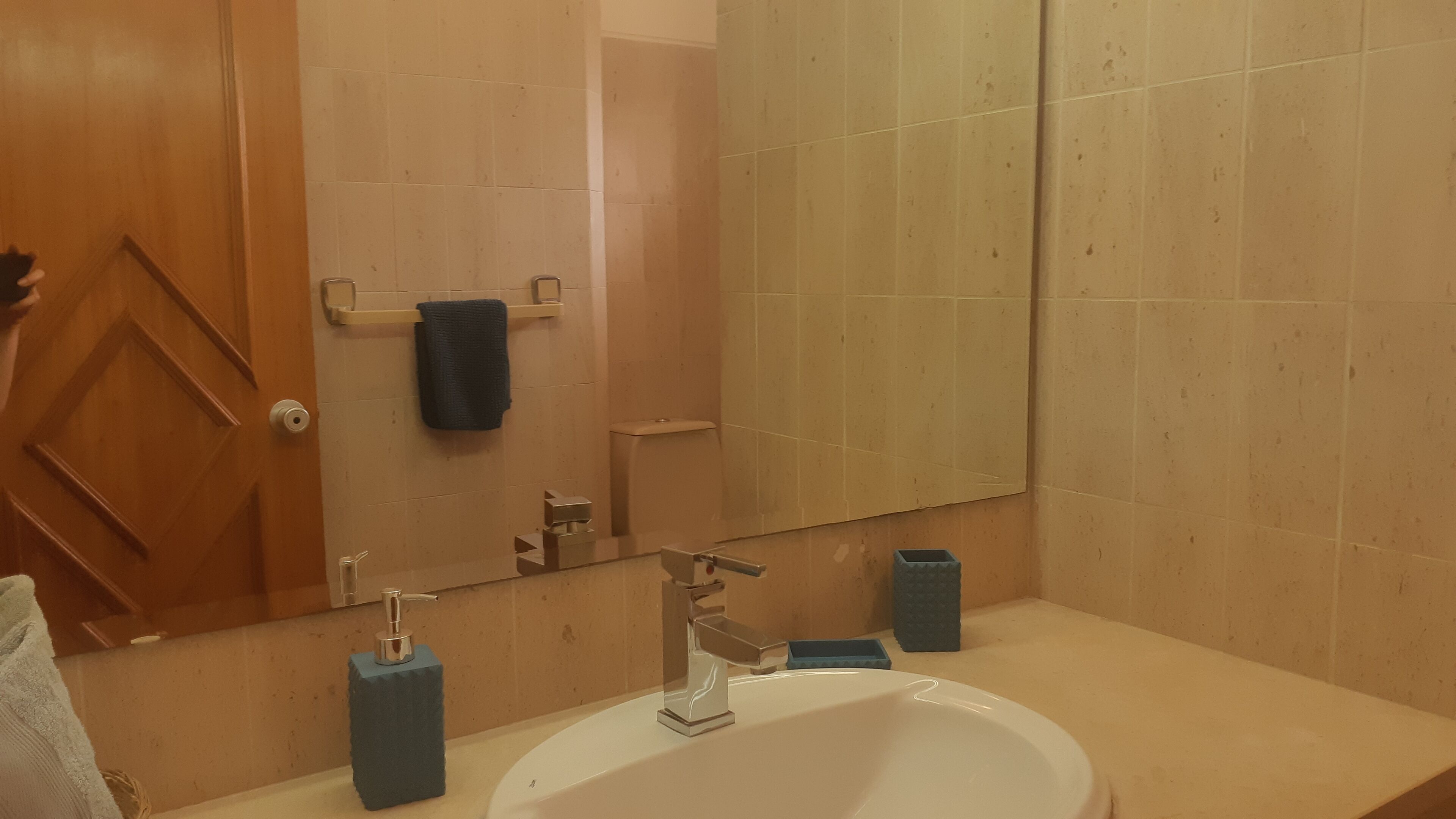 A bathroom with a white sink, a mirror, a towel rack, and a door.