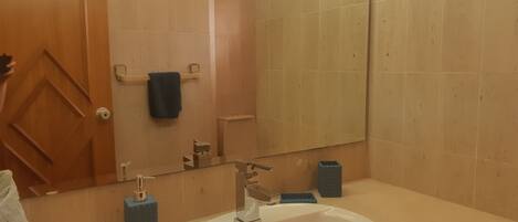 A bathroom with a white sink, a mirror, a towel rack, and a door.