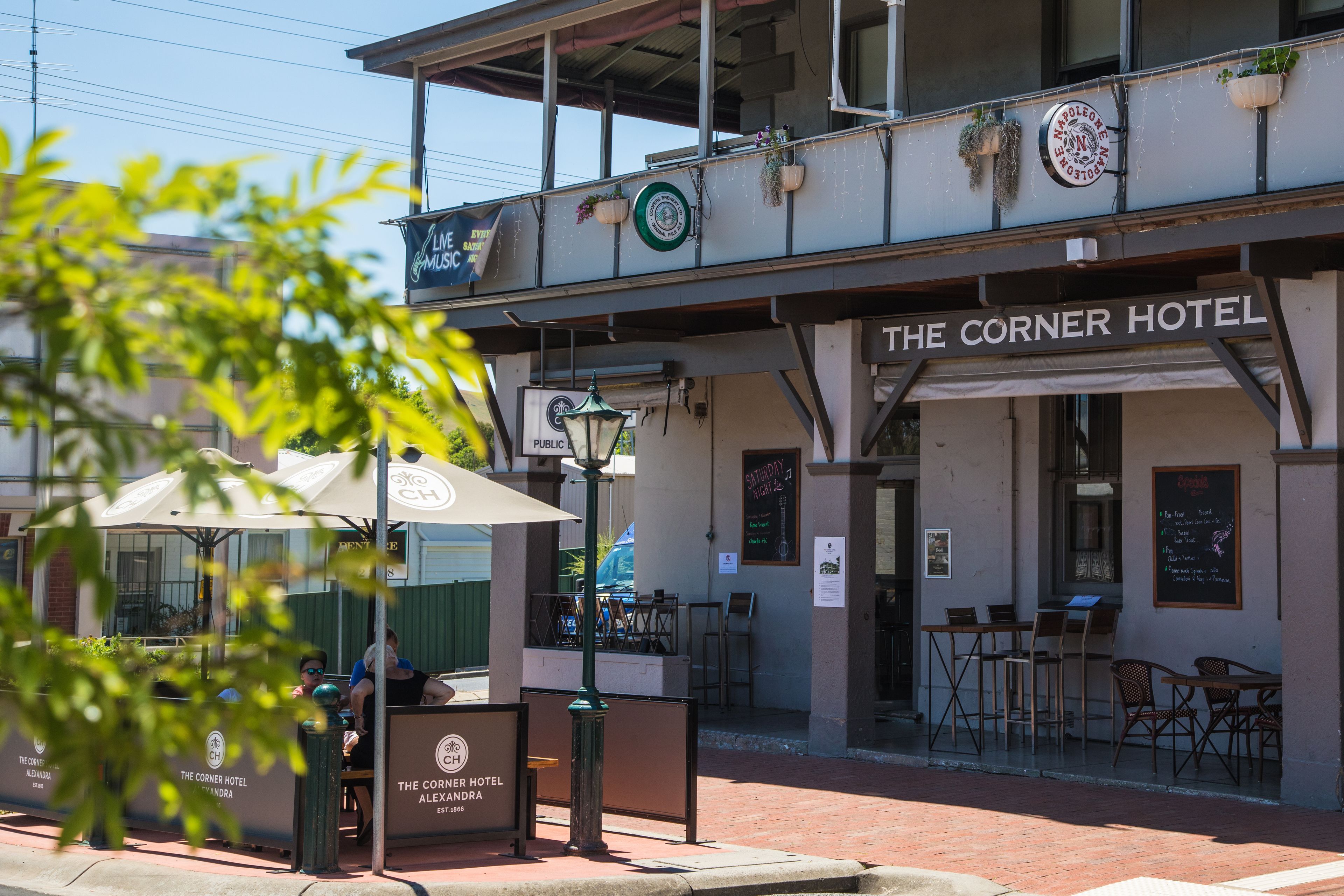The Corner Hotel with outdoor seating and a signboard.