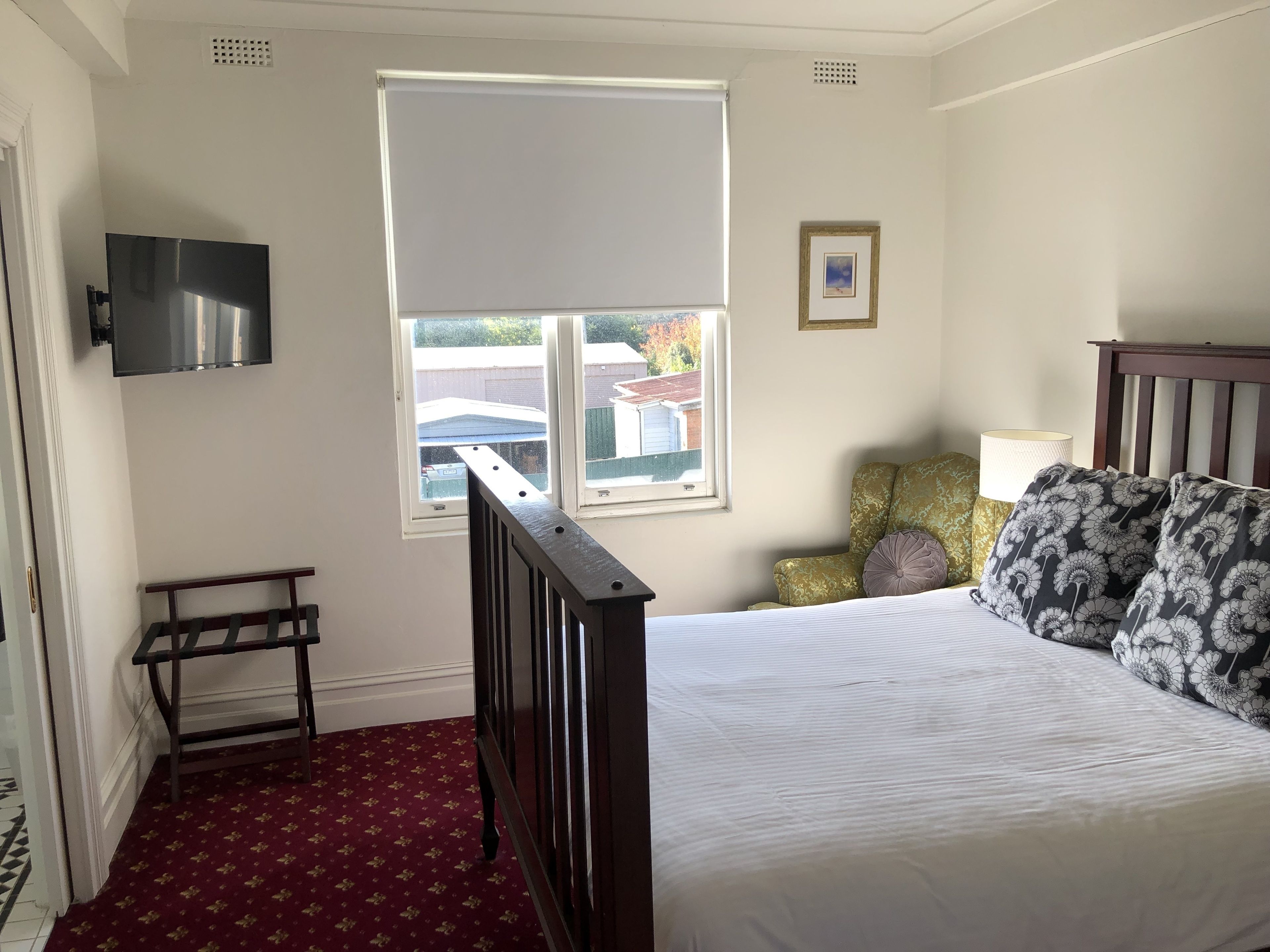 Ein Schlafzimmer mit Bett, Fenster, Sessel und Fernseher.