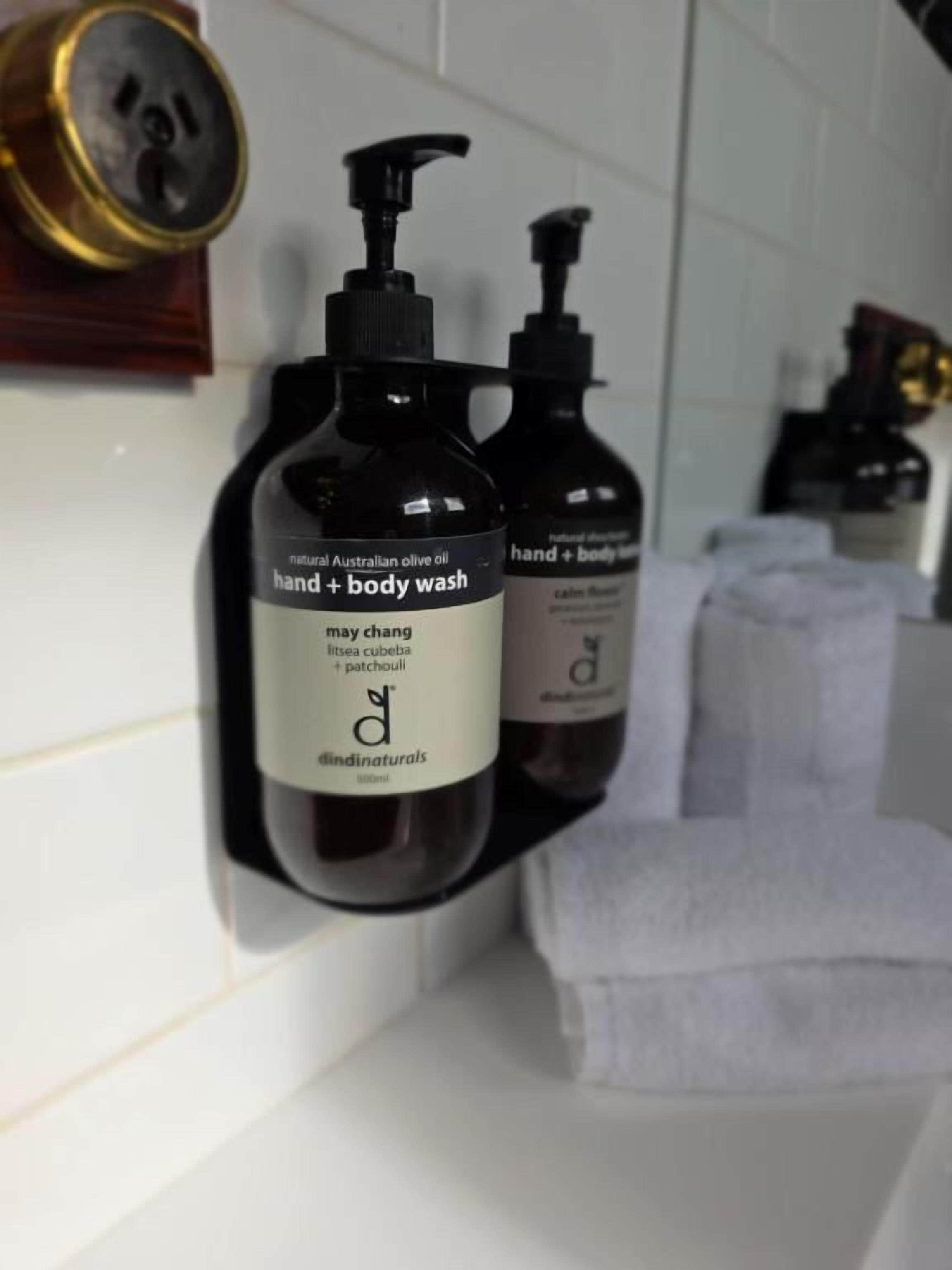 Deux bouteilles de savon pour les mains et le corps sont posées sur une étagère dans la salle de bain.