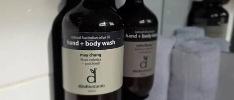 Two bottles of hand and body wash on a bathroom shelf.