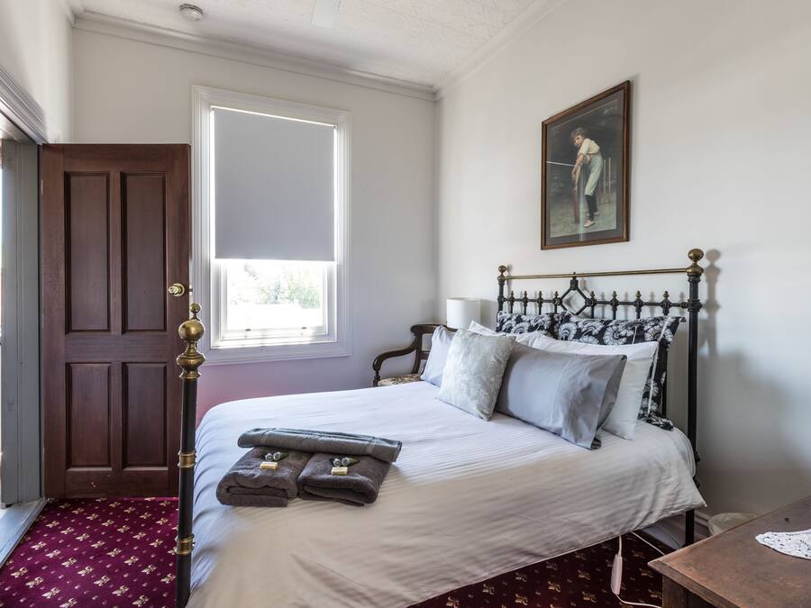 Quarto com cama, porta de madeira, janela e um quadro na parede.