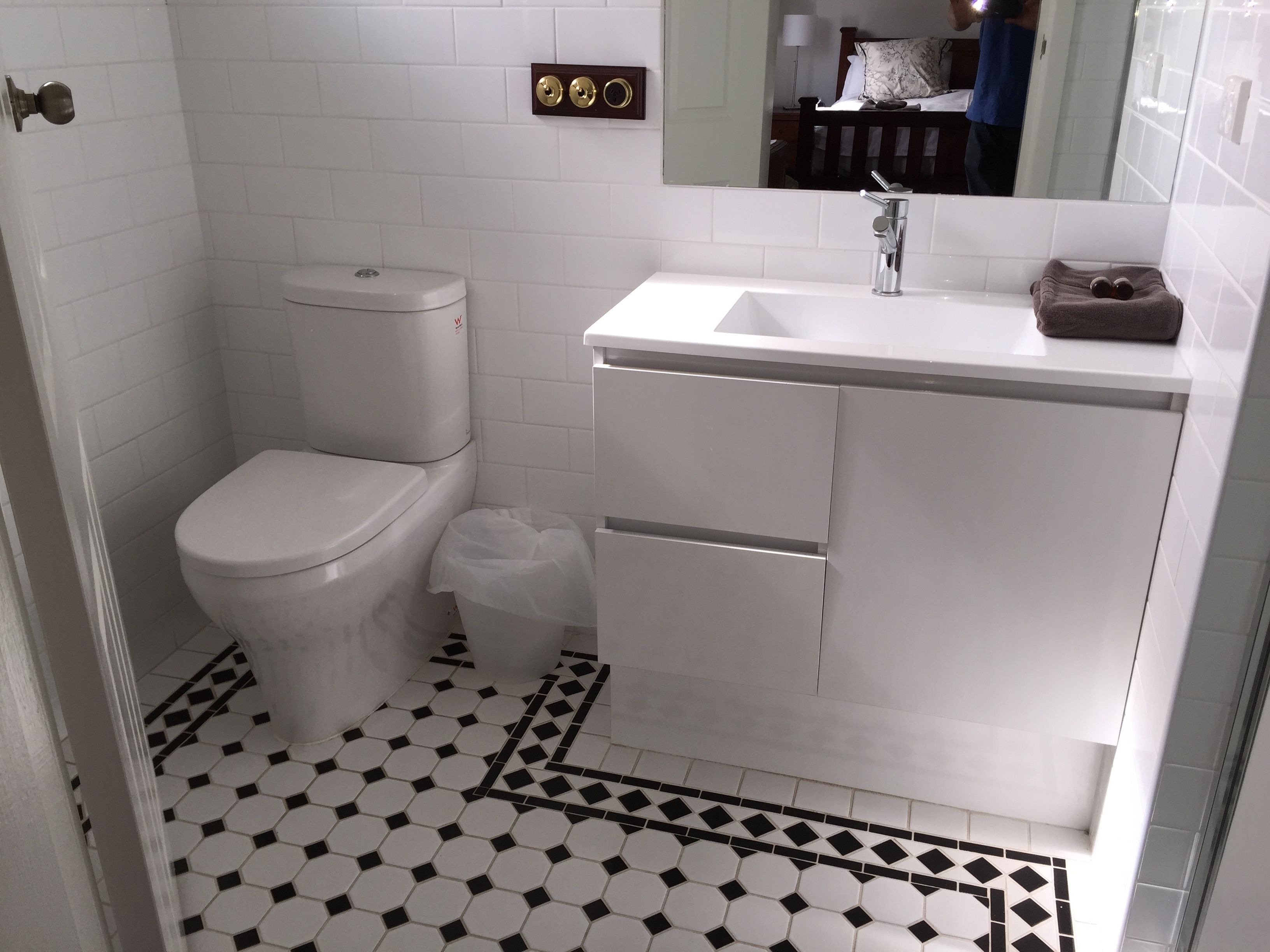 A bathroom with a toilet, sink, and mirror.