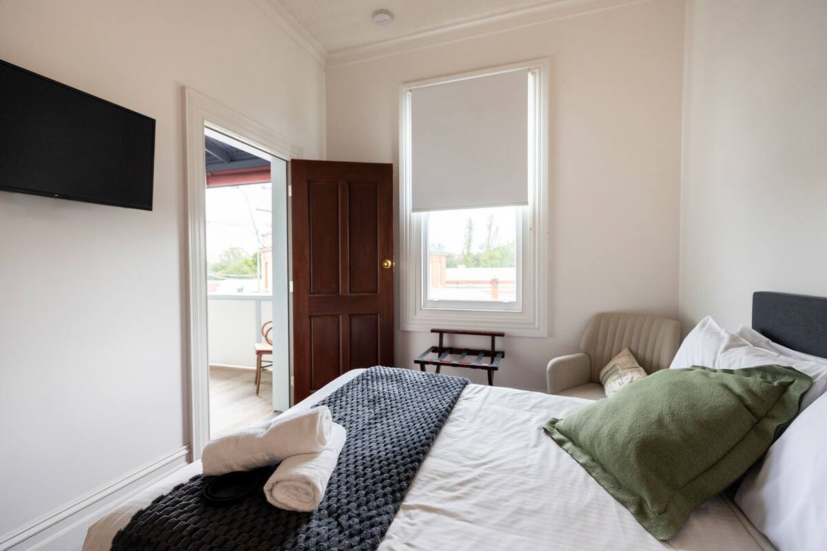 Une chambre à coucher avec un lit, une chaise, une fenêtre et une porte.
