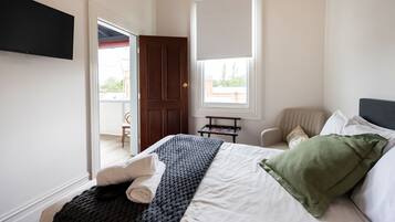 A bedroom with a bed, a chair, a window, and a door.