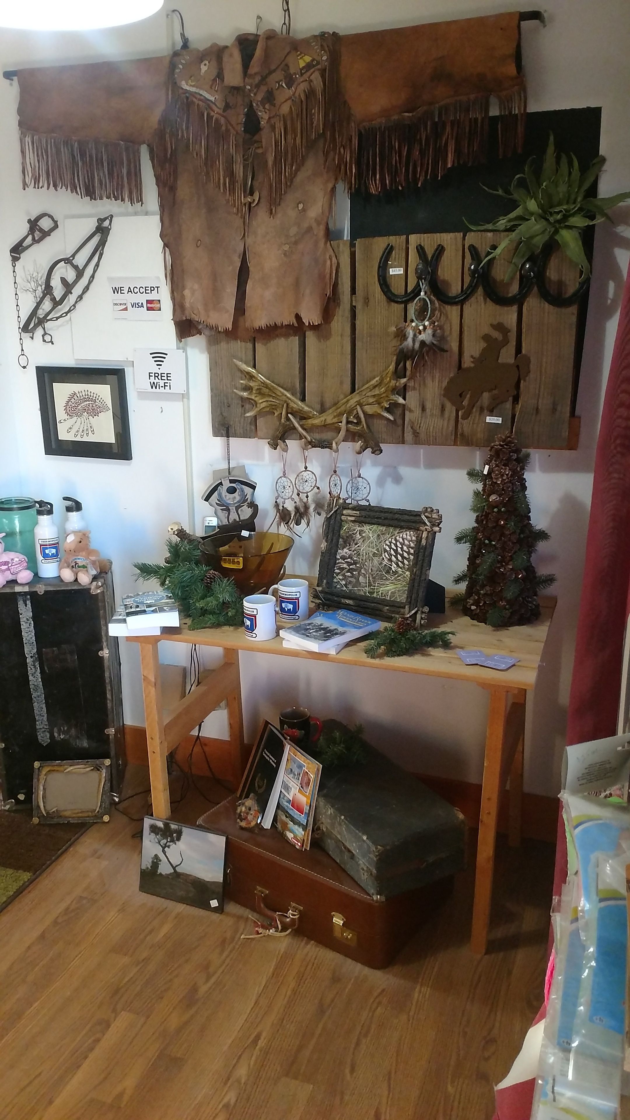 Een kamer met een houten tafel waarop verschillende voorwerpen staan, waaronder een fotolijstje, mokken en een kleine kerstboom.