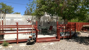 A patio with a table and chairs, a wooden bench, and a decorative fence with a star ornament. - Roundtop Mountain Vista - Cabins and Motel (Thermopolis)