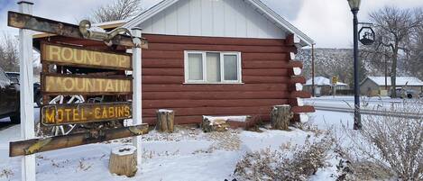 A rustic log cabin with a sign indicating it is a motel and a mountain round trip.