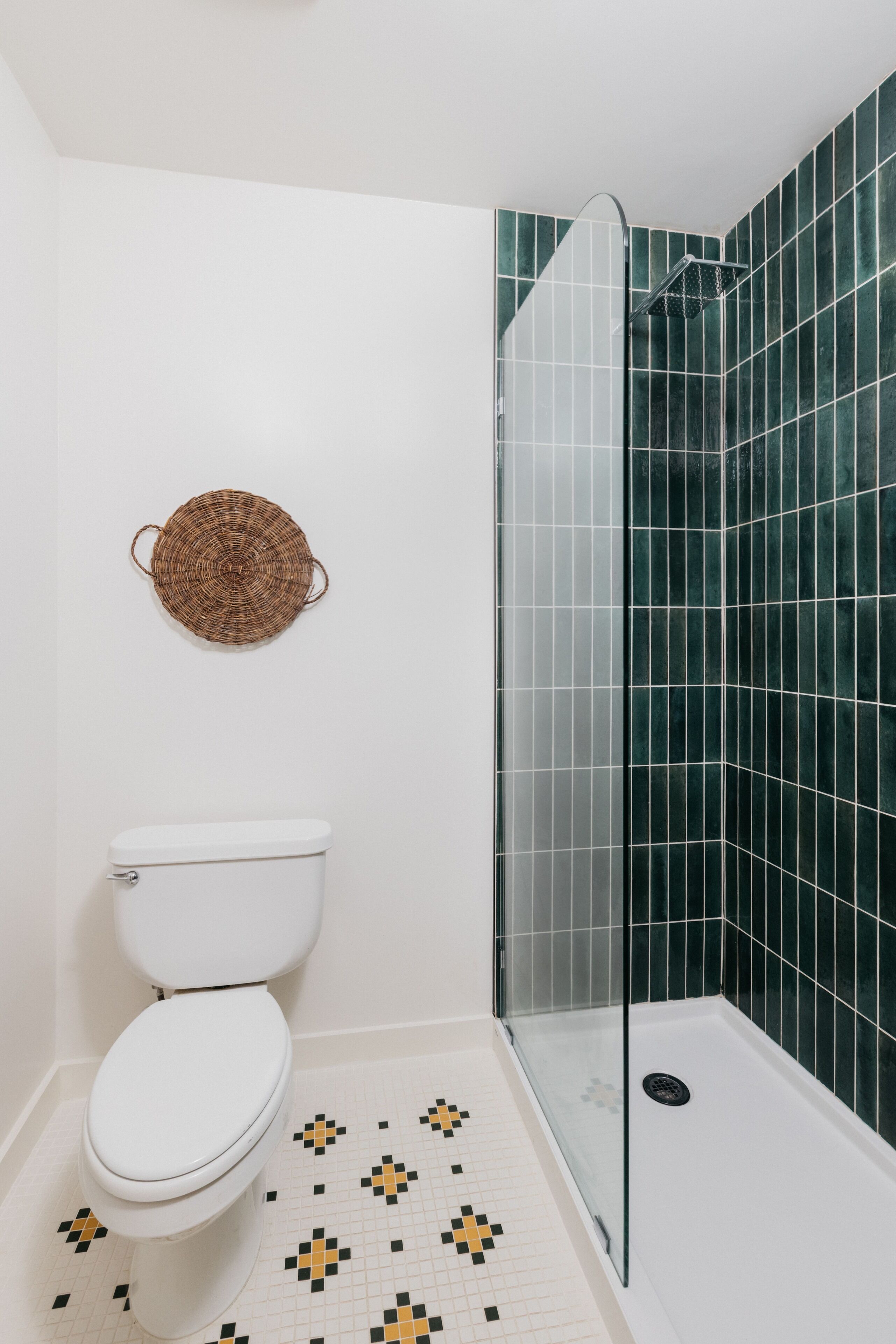 A bathroom with a toilet, a shower with a glass door, and a patterned floor.