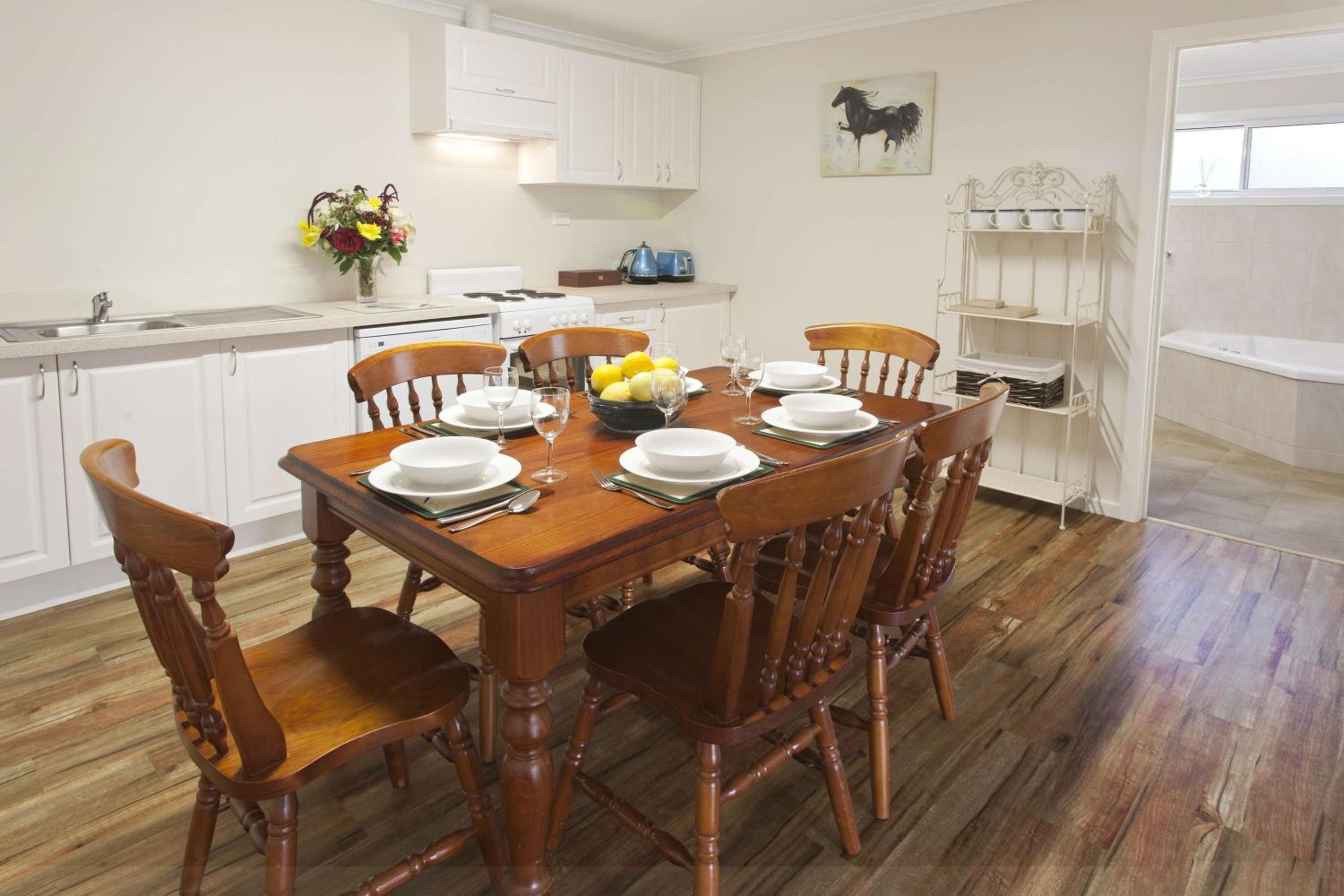 Un coin repas avec une table en bois dressée pour six personnes, entourée de chaises en bois.
