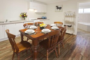 A dining area with a wooden table set for six, surrounded by wooden chairs.