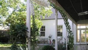 Un espacio exterior cubierto con un edificio blanco, vegetación y una bicicleta.