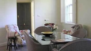 Un comedor con una mesa de vidrio, sillas y un florero con flores.