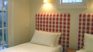 Una habitación con dos camas, cada una con un cabecero a cuadros y almohadas blancas.