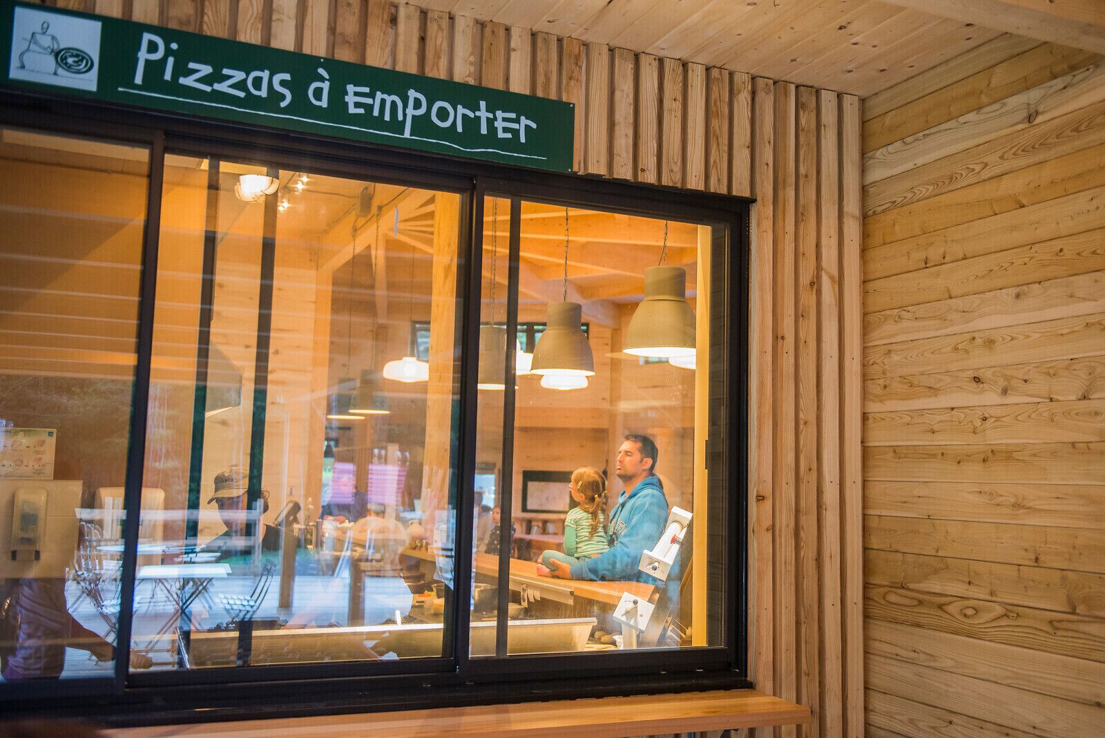 A restaurant with a wooden interior and a sign reading "Pizzas à Emporter".