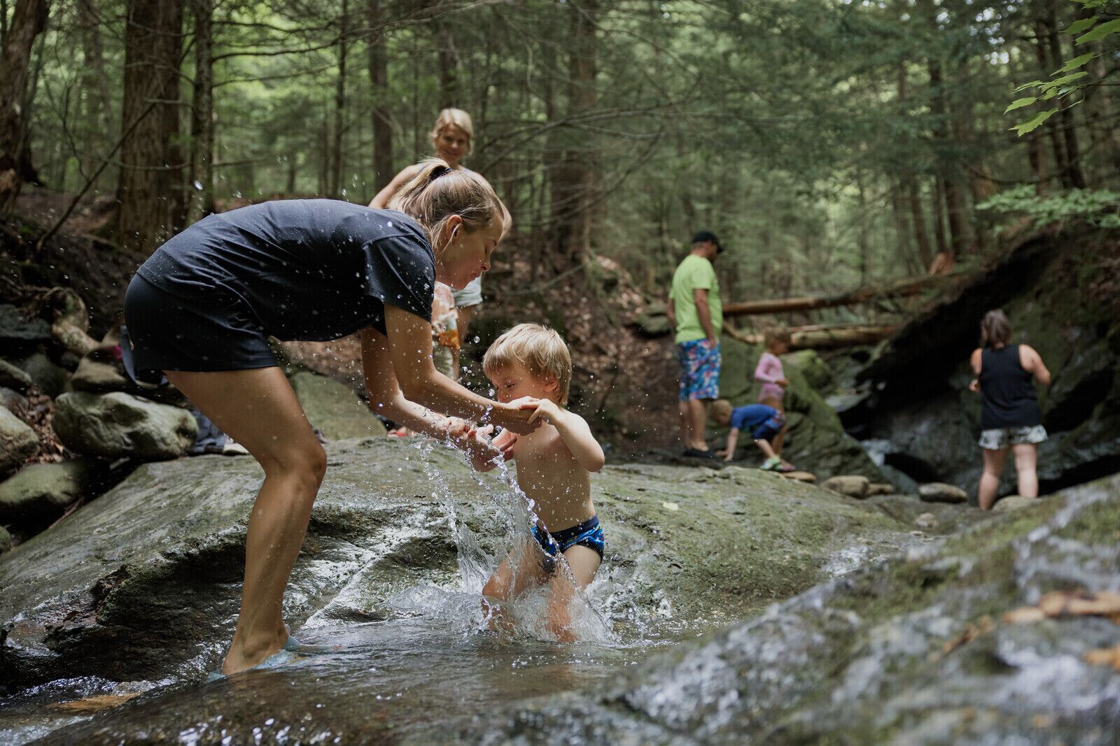 Un cadre naturel avec un ruisseau rocheux où les gens profitent de l'eau.