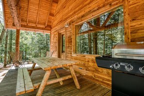 A wooden cabin with a picnic table and a grill.