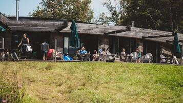 A rustic wooden building with outdoor seating and a grassy area in front.