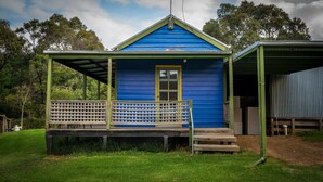 A small blue building with a porch and a door, surrounded by greenery. - Blue House at Mountainside Wines (Mount Cole)