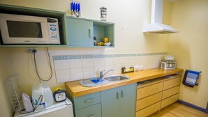 A compact kitchen with a microwave, sink, and wooden countertop. - Blue House at Mountainside Wines (Mount Cole)