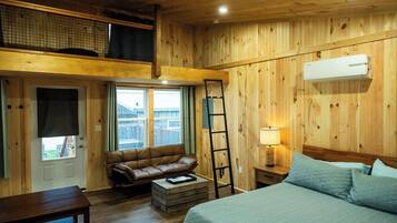 Una habitación con paneles de madera, una cama, un sofá, una escalera y una ventana.