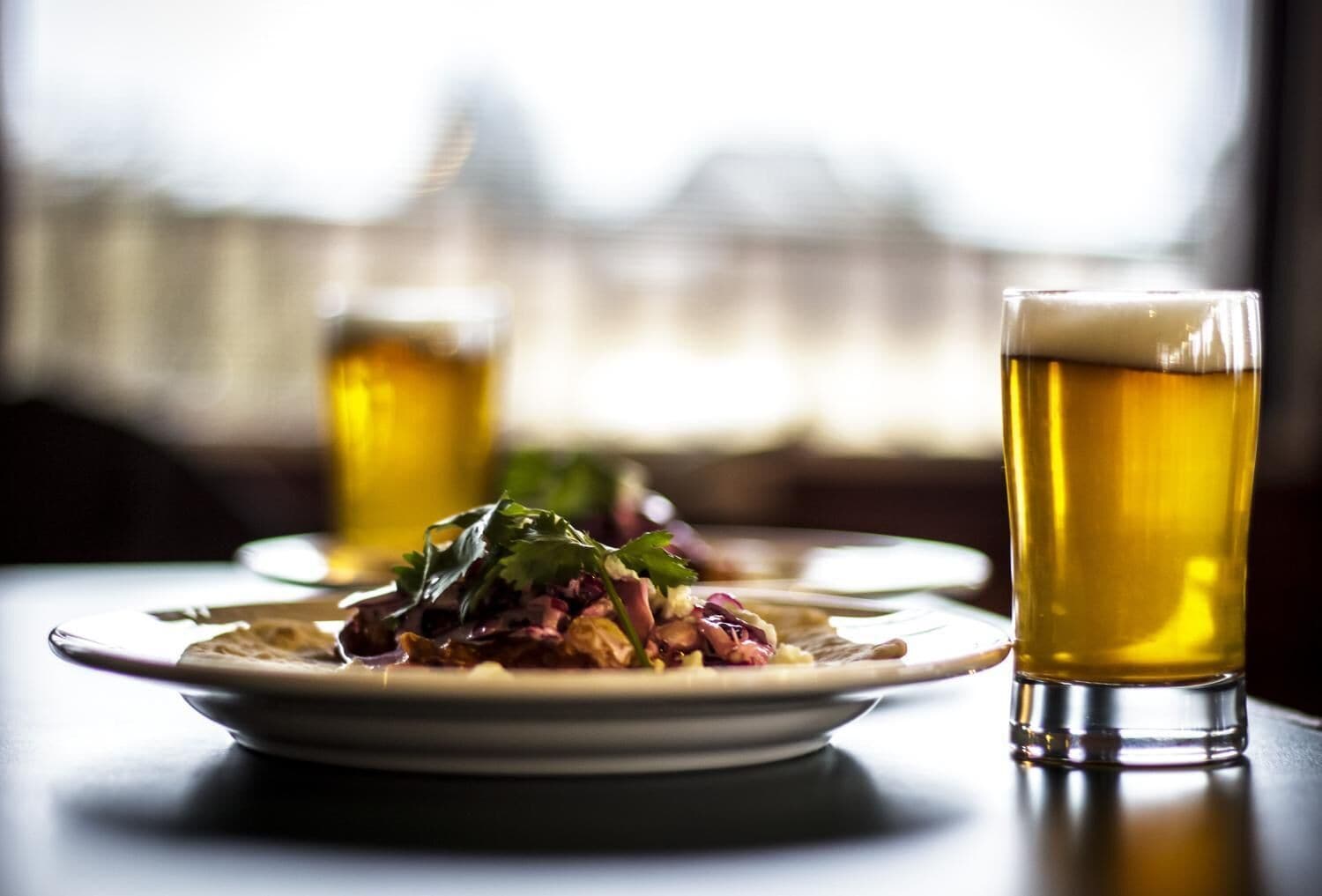 Un tavolo da pranzo con un piatto di cibo e un bicchiere di birra.