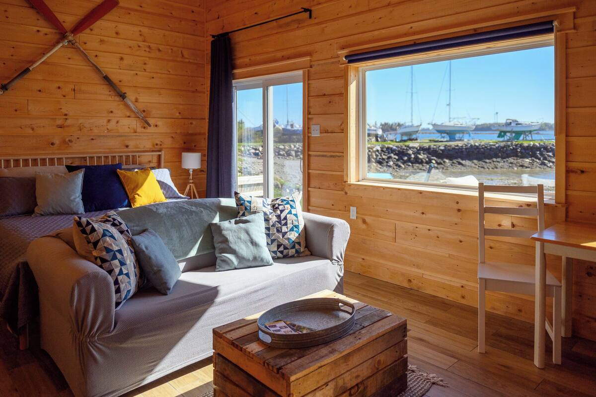 Una cabaña acogedora con cama, sofá y comedor.