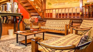 Una habitación acogedora con una escalera de madera, sofás estampados, una mesa de centro de madera y un mapa en la pared.