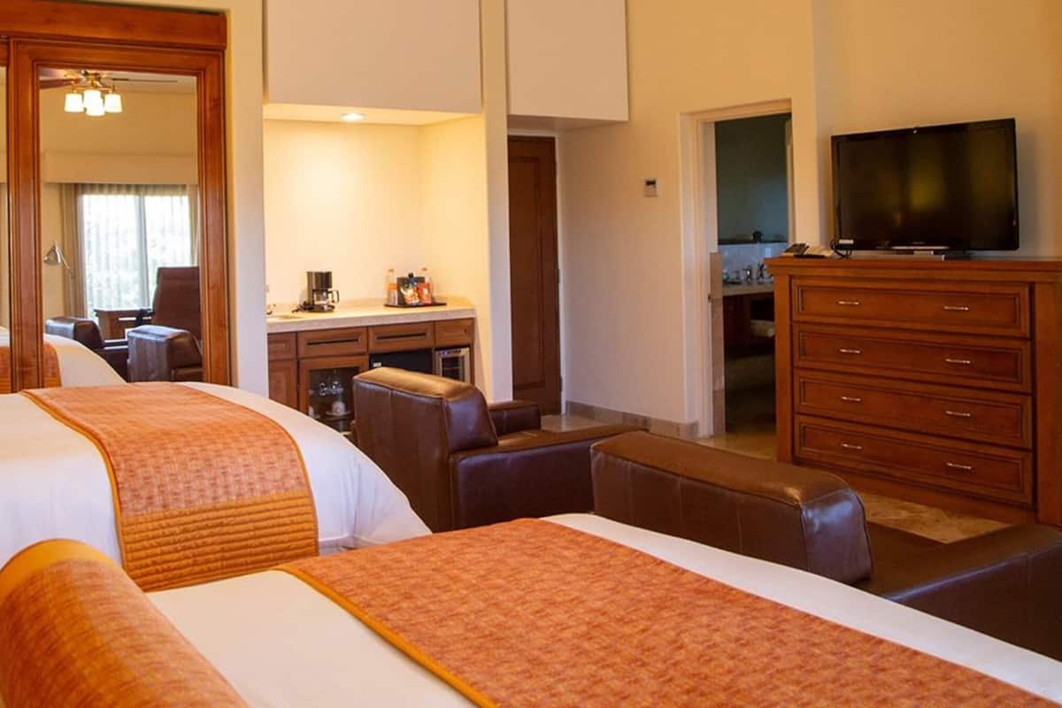 Ein Hotelzimmer mit zwei Betten, einem Schreibtisch, einem Fernseher und einem Kleiderschrank.