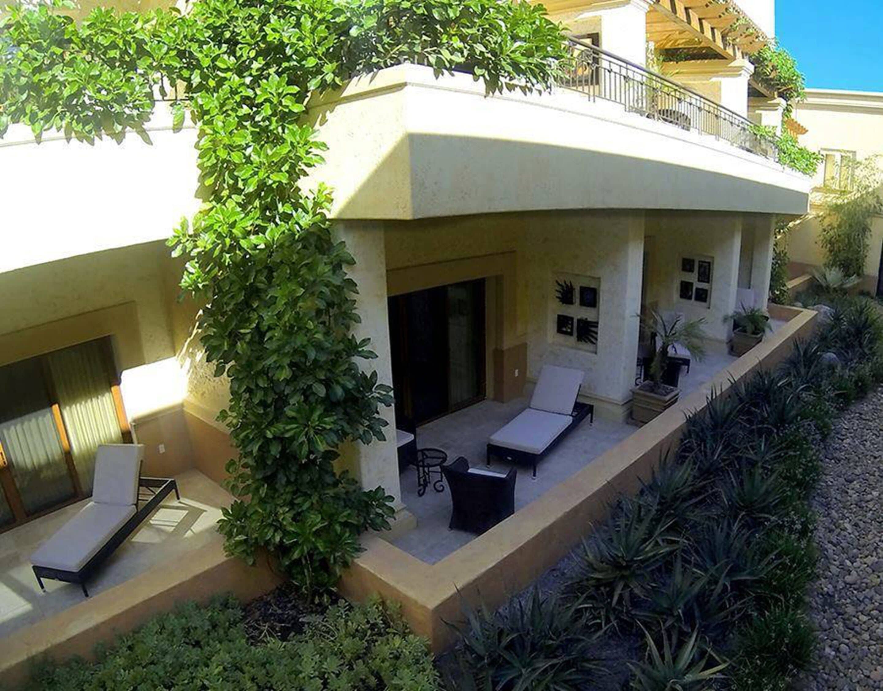 Un área de lounge moderna al aire libre, con piscina, tumbonas y una zona de estar cubierta.
