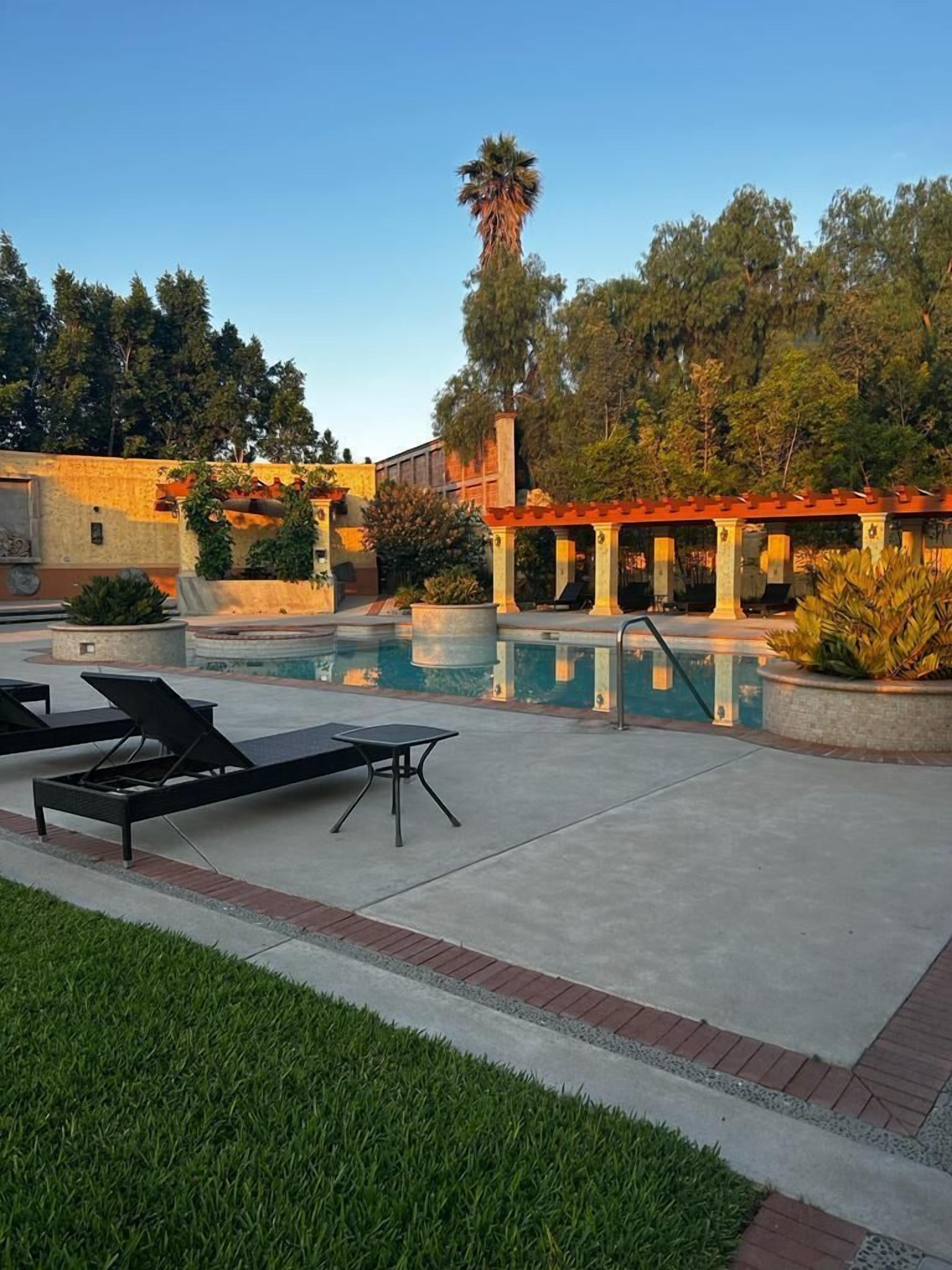 A pool area with lounge chairs and a pergola.