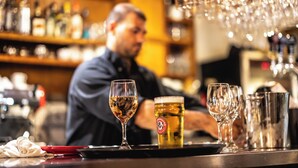 A bar setting with a bartender preparing drinks, glasses, and bottles on the counter. - Petit Hôtel Café Krieghoff (Québec City)