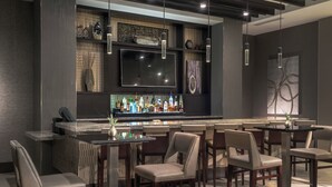 Un espace bar moderne doté d’un téléviseur à écran plat, de nombreuses bouteilles d’alcool et de tabourets de bar.