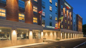 Un hôtel Courtyard Marriott avec une façade en briques, de nombreuses fenêtres et une entrée bien éclairée.