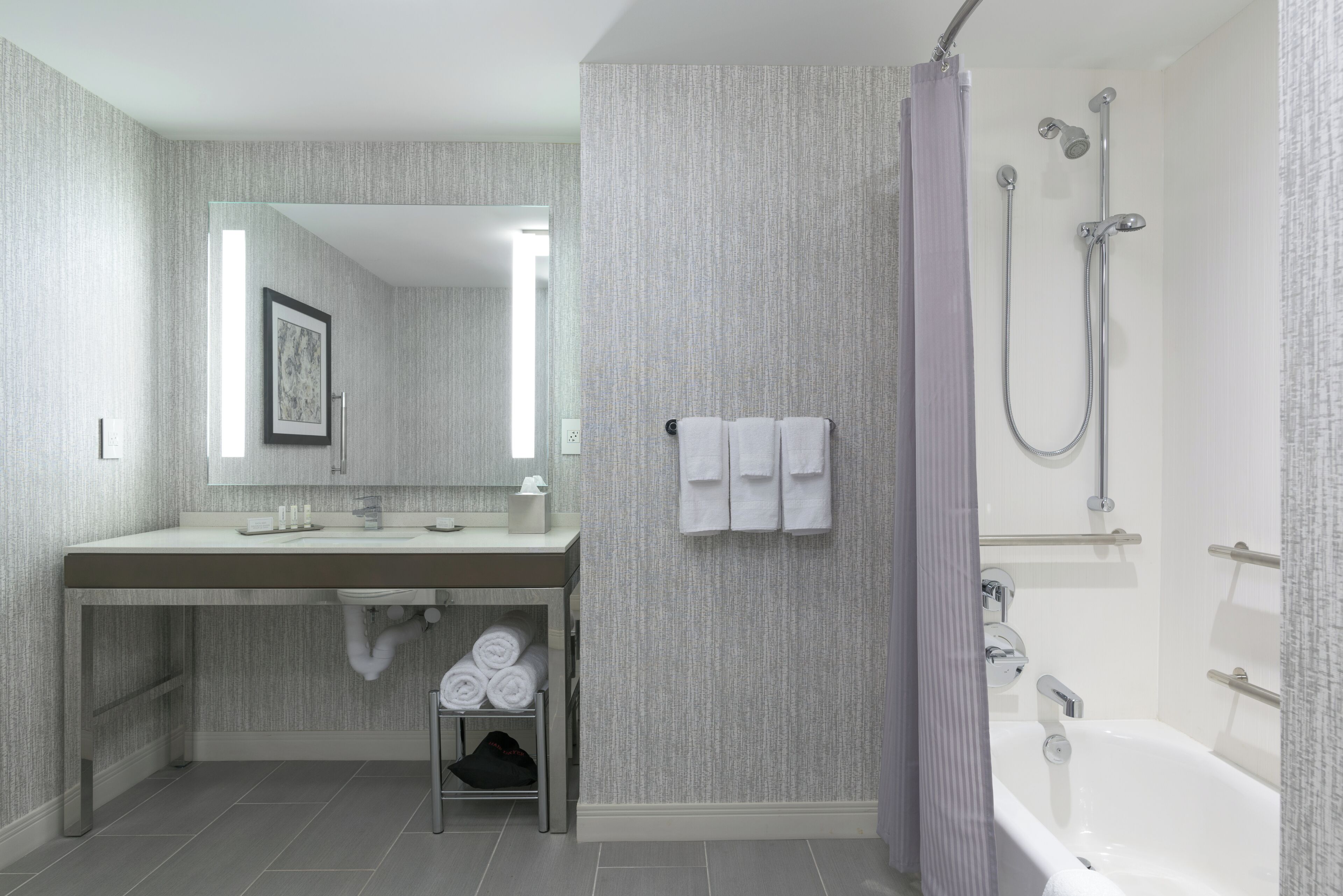 A modern bathroom with a large mirror, a sink, and a shower area.