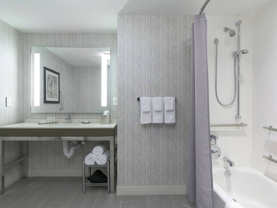 A modern bathroom with a large mirror, a sink, and a shower area.