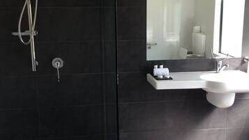 Un baño moderno con cabina de ducha de vidrio, un espejo grande y un lavabo blanco.
