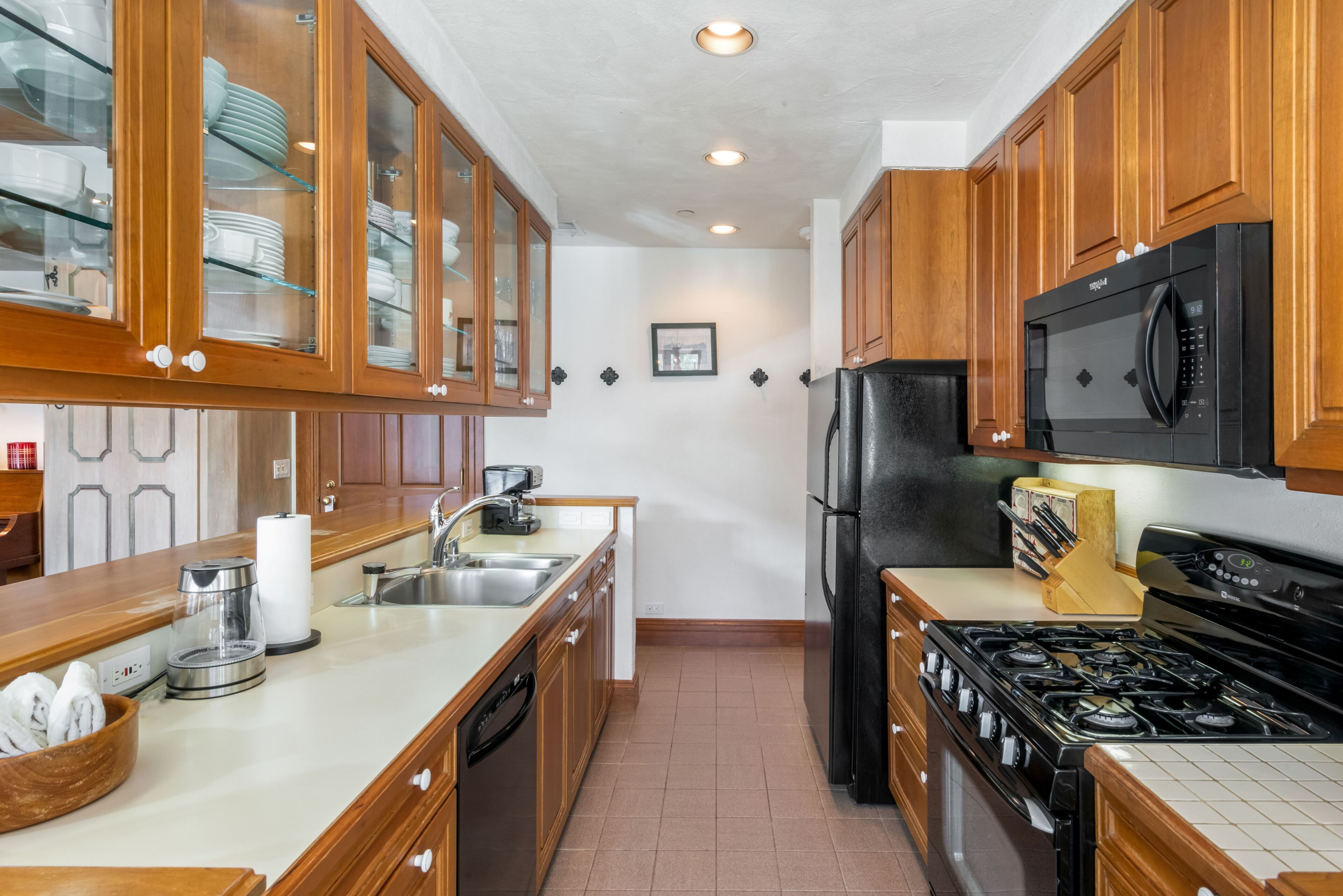 Una cocina con armarios de madera, un refrigerador negro, una estufa y un microondas.