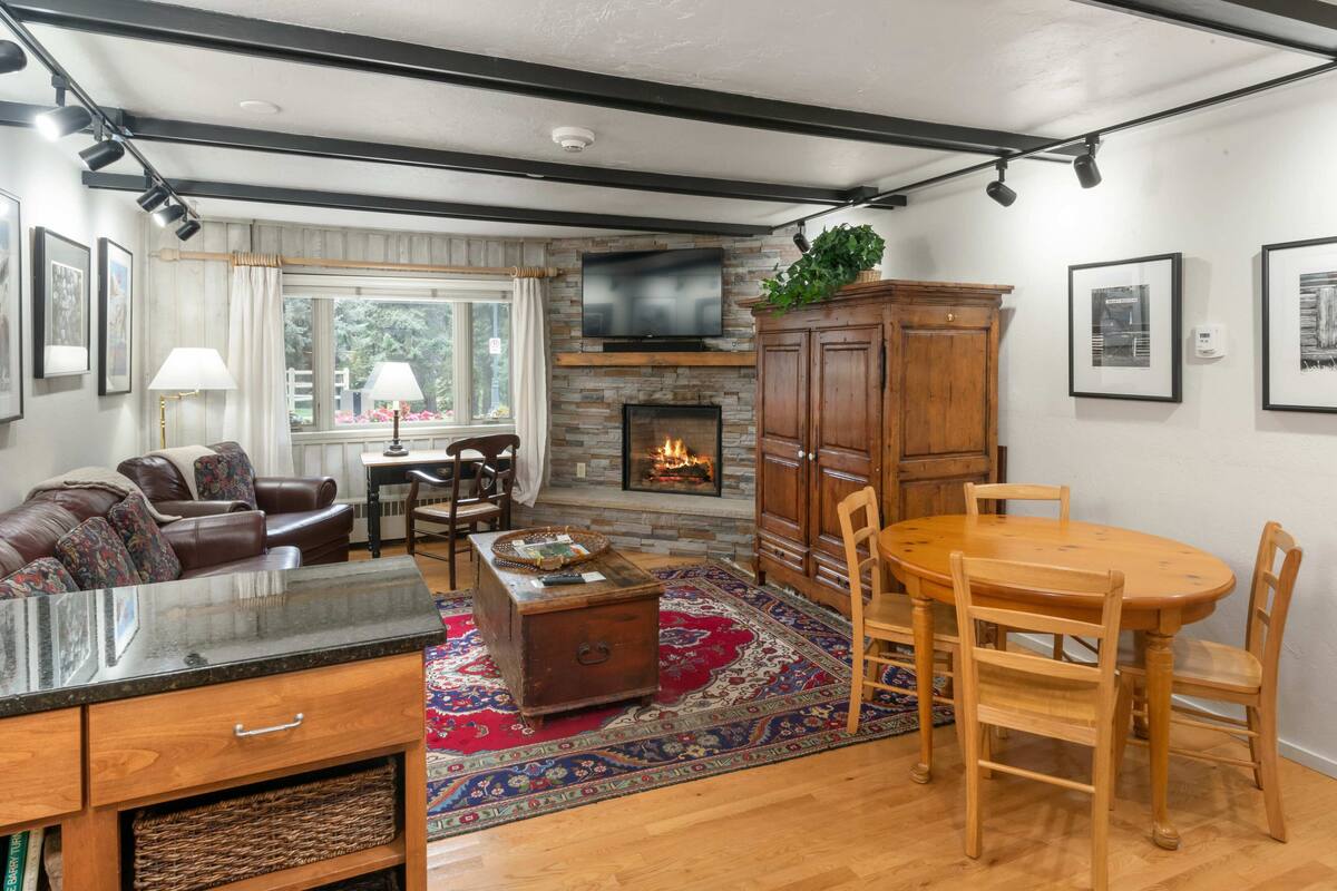 A living room with a fireplace, wooden furniture, and a television mounted on the wall.